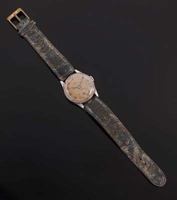 a close up of a watch on a black surface with a black background
