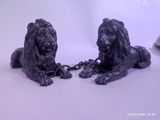two statues of lions chained to chains on a white surface