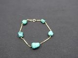 a bracelet with turquoise beads on a black surface