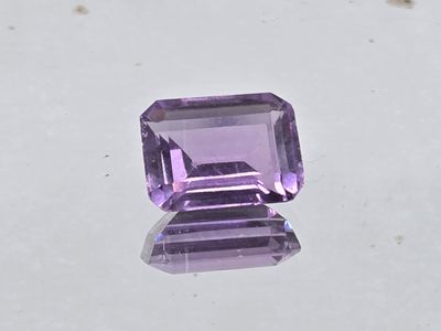 an amethorate cut purple stone sitting on top of a white surface