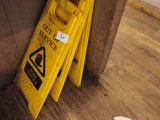 a yellow caution sign sitting on the floor next to a yellow caution sign