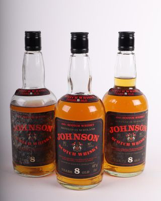 trois bouteilles de whisky posées l'une à côté de l'autre sur une table