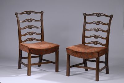 deux chaises en bois avec des assises recouvertes de cuir, posées sur une surface blanche