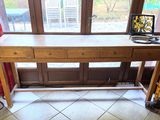 une table en bois sur laquelle est posé un ordinateur portable, devant une fenêtre