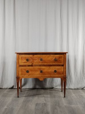une commode en bois posée contre un rideau blanc