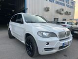 Une BMW X5 blanche garée devant un immeuble