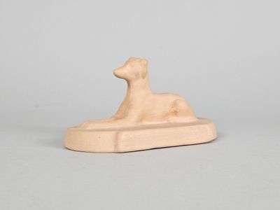 a small statue of a dog laying on top of a wooden block