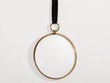 un miroir plaqué or suspendu à une lanière en cuir noir
