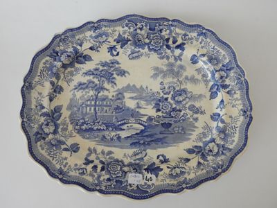 an old blue and white plate with a picture of a house in the background