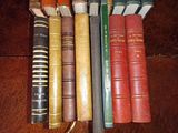 several old books are lined up on a wooden table