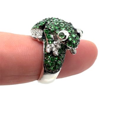 a person holding a ring with green and white stones on it
