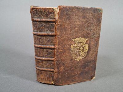 un vieux livre posé sur une table, surmonté d'une couronne