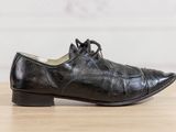 black leather shoes with laces on a wooden surface