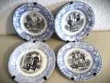 quatre assiettes bleues et blanches ornées de dessins représentant des personnes, posées sur une table