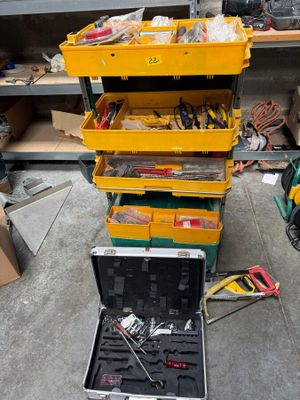 une boîte à outils jaune contenant des outils, posée par terre