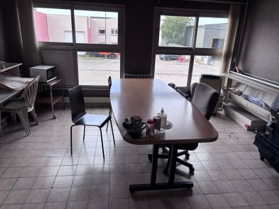 des tables et des chaises dans une pièce dotée d'une grande fenêtre donnant sur un parking