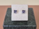 une paire de boucles d'oreilles en tanzanite posées sur un bloc de marbre