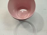 a pink bowl sitting on top of a table next to a plastic cup