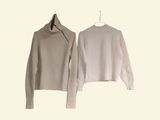 pair of white sweaters hanging on a hanger on a white wall