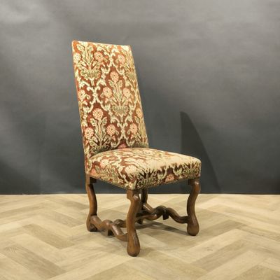 an old chair with a floral upholstered seat on a wooden floor