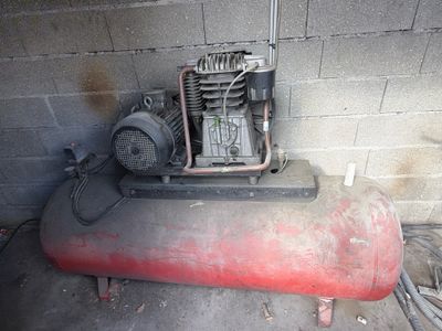 a small air compressor sitting on top of a red tank
