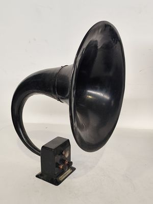 un vieux gramophone noir posé sur une surface blanche, avec un fond blanc