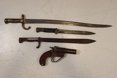 trois types d'armes différents sont exposés sur une surface blanche