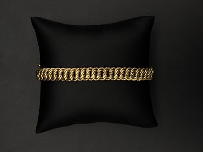 un bracelet en chaîne d'or posé sur un coussin noir