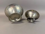 pair of silver vases on a table with a white background