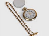 a gold pocket watch and a chain on a white surface