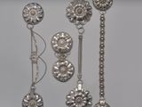 cinq cuillères en argent et une paire de boucles d'oreilles posées sur une table