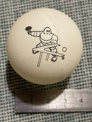 une balle blanche sur laquelle est dessiné un homme jouant au ping-pong