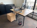 a desk with a computer and a trash can in the corner