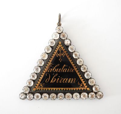 un gros plan d'un pendentif en forme de triangle orné de diamants