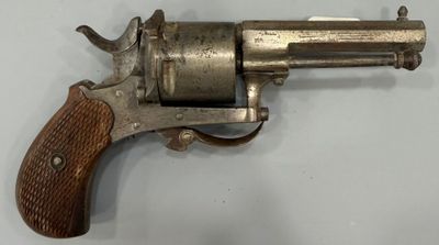 gros plan d'un revolver avec une poignée en bois sur une surface blanche