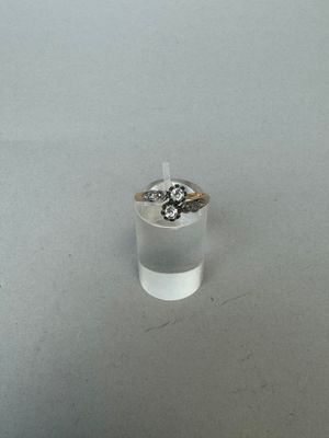 un gros plan sur une bague posée sur une table, avec une bougie en arrière-plan