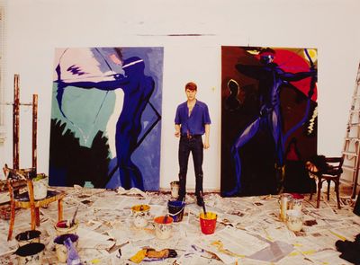 a man that is standing in front of some paintings