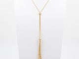 a gold necklace with a long chain and a tassel on a mannequin neck