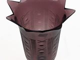 a purple vase with a design on it on a white surface