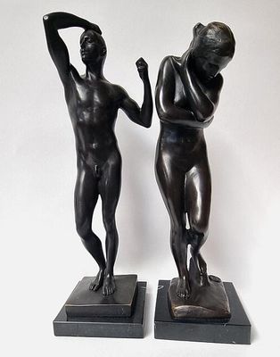 pair of bronze statues of a man and woman on marble bases