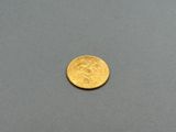 a close up of a gold coin on a gray surface
