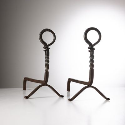 une paire de bougeoirs anciens en fer, posés sur des socles, sur un support blanc