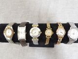 several different watches are displayed on a black display stand