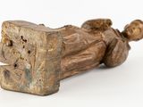 a wooden statue of a man laying down on the ground