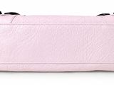 the pink purse is sitting on a white surface with a black handle