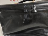 a person holding a black leather bag with a handle