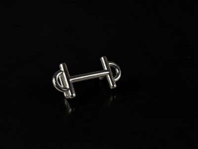a close up of a pair of silver earrings on a black surface