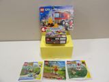 une boîte de Lego posée sur une table à côté d'un camion de pompiers en Lego