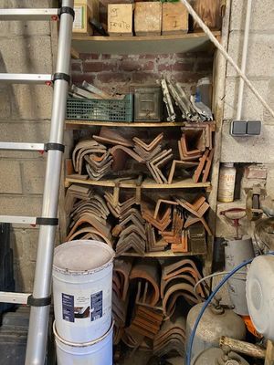 une échelle appuyée contre un mur de briques, à côté d'un tas de bois