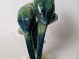 two green birds that are sitting on top of a table